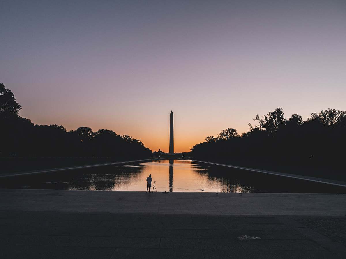 dusk silhouette photo of person standing near body of water sunrise